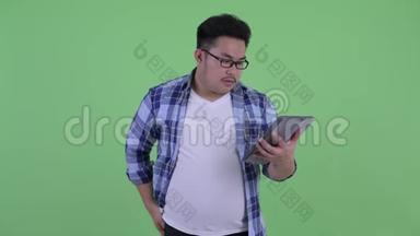 快乐年轻、体重超重的亚洲时髦男人使用手机和数码平板电脑