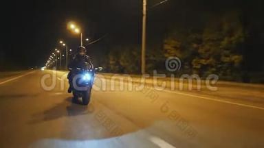戴着头盔的年轻人骑着现代运动摩托车在傍晚的城市街道。 骑摩托车的摩托车