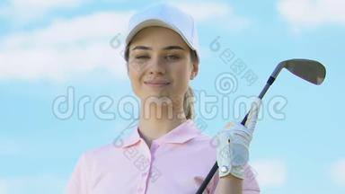 穿着高尔夫球衣，在镜头前摆着俱乐部姿势的迷人女人，奢侈的爱好