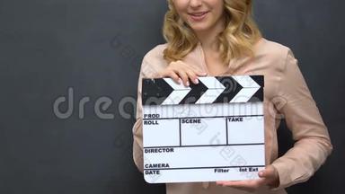 一<strong>位</strong>年轻女士在黑板背景电影拍摄中用孤立的<strong>挡</strong>板拍手