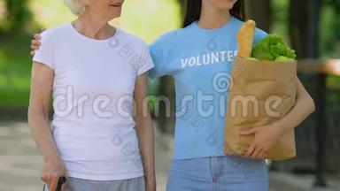 <strong>志愿者</strong>带着拐杖给老残疾女士送食物，在医院公园散步