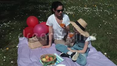 母亲和女儿在草地上野餐放松。 夏季野餐概念
