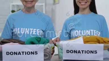 善良的女士志愿者展示盒子和衣服相机捐赠穷人