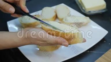 女人把黄油涂在白面包上。 双手合拢涂抹面包上的黄油。 用玛格丽特做罐头。 家庭烹饪
