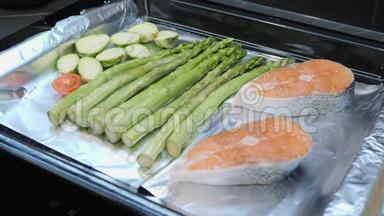 烤箱煮蔬菜的过程。 新鲜的西红柿，甘蓝和绿芦笋放在烤箱托盘上。 健康饮食。 支票