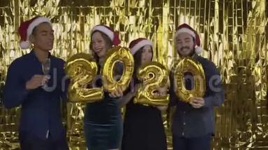 2020年 落下的金色纸屑。 4个带着金箔字母的人在金色的背景上跳舞。 红色