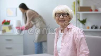 微笑的老妇人看着相机，管家在<strong>房间</strong>里擦拭灰尘，<strong>打扫</strong>卫生