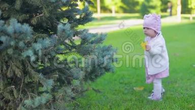 一个穿着粉色衣服、黄秋色漂亮叶子的可爱<strong>小女孩</strong>在公园附近的一棵树上<strong>奔跑</strong>，跌倒在绿草上