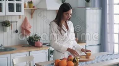 穿着白色浴袍的女孩在厨房吃切片苹果，<strong>看</strong>着<strong>窗外</strong>慢动作