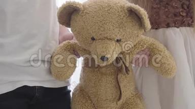 特写小男女白种人双手抱着泰迪熊。 两个朋友分享的软玩具