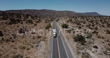 在炎热的夏天，美国亚利桑那州，Drone在沿着美丽的砂岩沙漠山路行驶的大型送货卡车上倾斜下来。