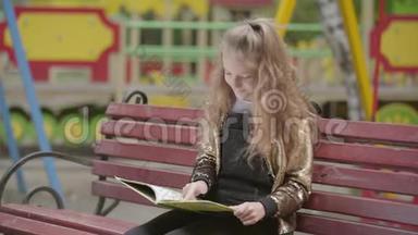 可爱的<strong>少女</strong>正在户外坐在长凳上<strong>看书</strong>。