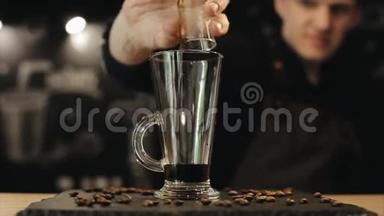男咖啡师把<strong>黑糖</strong>浆倒在拿铁玻璃杯里，放在咖啡豆柜台上