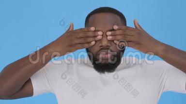 非裔美国人用双手闭上眼睛。 蓝色的<strong>背景</strong>。 4K