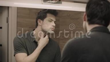 年轻人在浴室镜子前刮脸。 帅哥画像