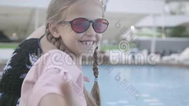 小可爱，扎着小辫子，成熟的女人坐在池边，在镜头里微笑，露出拇指