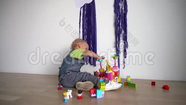 小可爱男孩用彩色积木搭建，坐在木地板上.. 万向节运动
