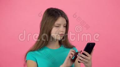 女孩在<strong>视频</strong>聊天，在演播室的手机与<strong>粉红</strong>色背景。 慢动作