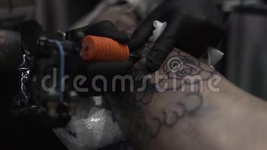 一个纹身艺术家的特写在一个男人`腿上纹身。 很高的分辨率。 专业纹身师在工作室工作。 特写v