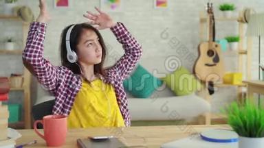 美丽的亚洲女孩，留着长发，坐在现代化的客厅里，带着耳机听音乐，放松身心
