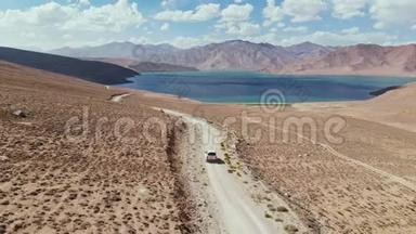 在4x4路的高空，汽车沿着砾石小径驶向干旱山区的湖泊。 帕米尔公路丝绸之路