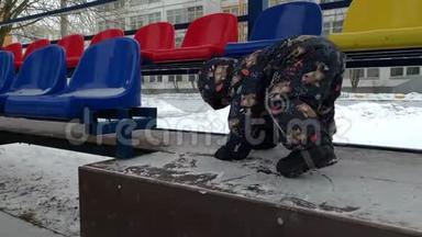 一个穿着冬季连衣裙的<strong>小孩</strong>子爬上了台阶。 俄罗斯的<strong>冬天</strong>。 体育论坛。 黄昏。