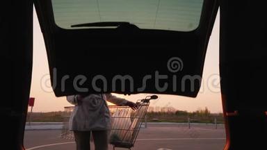 从汽车后备箱看：一个女人在停车场的汽车后备箱里储存一家商店的包裹