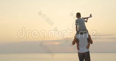 快乐的<strong>父子</strong>在日落时一起玩飞机玩具，幸福的家庭在户外<strong>散步</strong>。