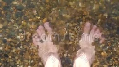 一个人光着脚在海边的鹅卵石滩上特写，水洗了一个人的腿