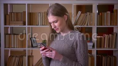 年轻有魅力的女学生在手机上浏览社交媒体，在手机上看镜头的特写肖像。