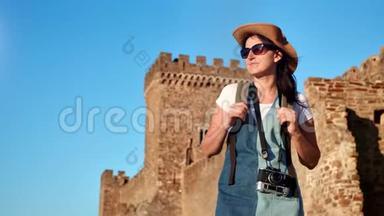 微笑的时尚背包客游客妇女在中世纪城堡放松背景中镜头