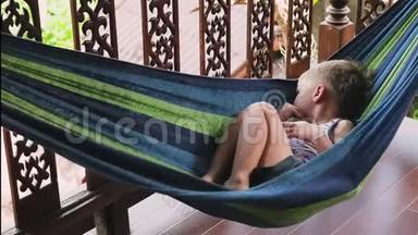 一个快乐的小男孩躺在<strong>吊床</strong>上玩耍。 夏天，小男孩躺在阳台上的<strong>吊床</strong>上。
