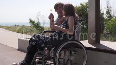 一个年老的男人在轮椅上给他的妻子一朵花。