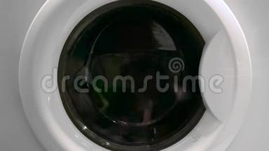 洗衣机门的特写，衣服在里面旋转。 概念。 洗衣机的特写镜头