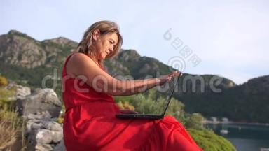 一个漂亮的女人在一台笔记本电脑上完成工作，这台笔记本电脑<strong>高挂</strong>在海面上的岩石上，动作很慢