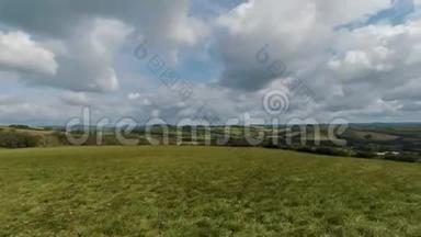 英国乡村的画面，起伏的山峦，绿色的田野，壮丽的蓝天和巨大的白云下的树木