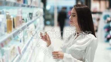 化妆品店的女人肖像选择面霜，嗅它，慢动作