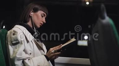 年轻女子或乘客看书，坐在<strong>公共交通工具</strong>听音乐，拍摄稳定。 慢动作。 城市