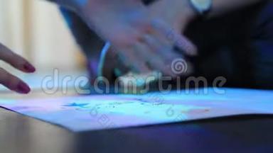 一男一女在霓虹灯下画着一张Whatman。