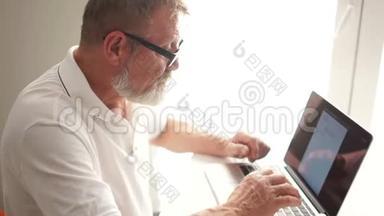 工作中的作家或科学家。 一位老人用电脑写一封信，远程就业。 成熟的男人用
