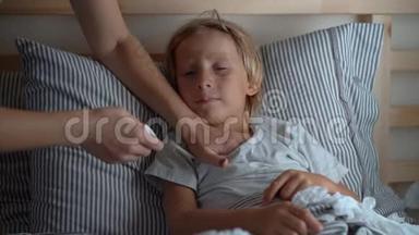 在床上生病的小男孩。 母亲用精油`男孩的胸部涂抹药膏. 婴儿流感概念