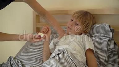 一个生病的小男孩躺在床上的超慢镜头。 母亲用精油`男孩的胸部涂抹药膏. 婴儿流感