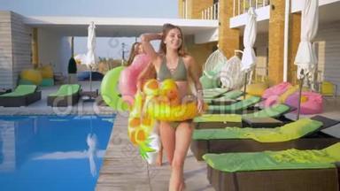 <strong>夏日</strong>度假期间，快乐迷人的女朋友们穿着带充气环的泳衣在<strong>游</strong>泳池附近散步