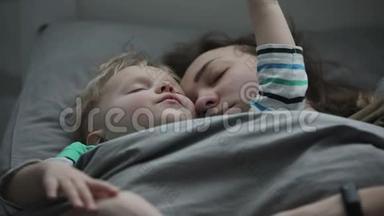 <strong>妈妈和宝宝</strong>一起午睡.. 一个年轻的女人<strong>和</strong>她的小儿子睡在床上。