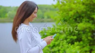 女孩使用智能手机沿河行走的侧视图