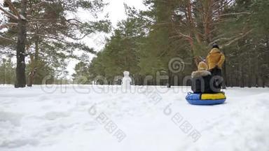 男人在冬季公园的雪地上滚动女人，后景。