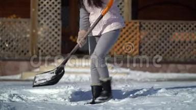年轻女子在房子附近的后院铲雪。