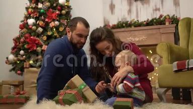 在房间里，妈妈、爸爸和小宝宝坐在地板上，和<strong>一家人</strong>一起庆祝<strong>圣诞节</strong>