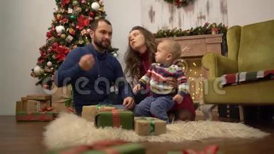 妈妈、<strong>爸爸</strong>和小宝宝坐在房间的地板上，装饰着圣诞节。 <strong>爸爸</strong>在玩<strong>小孩</strong>