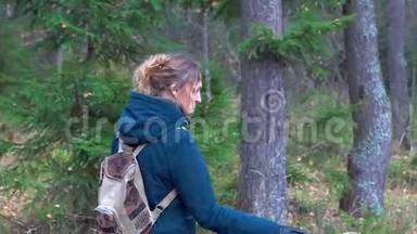 一个身材苗条的漂亮女人背着一个背包，手里拿着干草叶，走过秋天